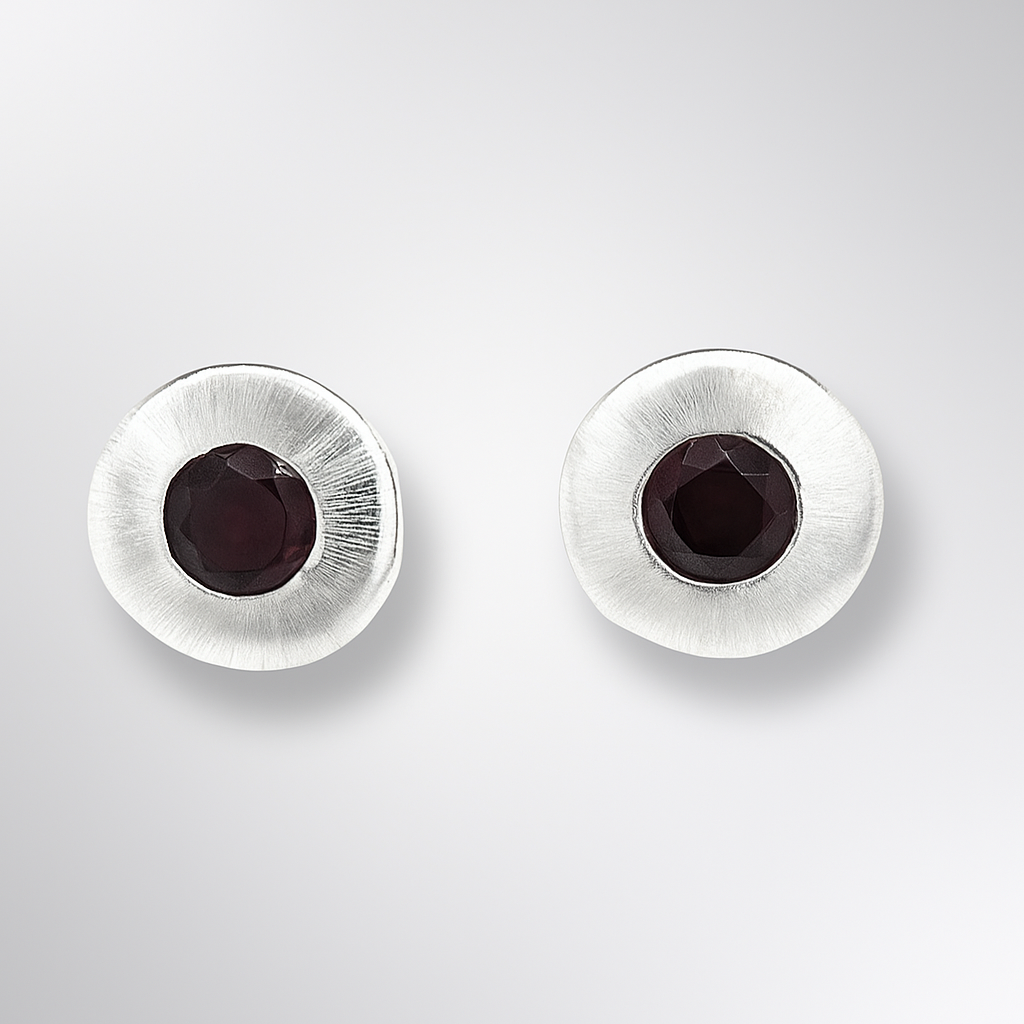 Pair of silver earrings with dark gemstones on a light gray background