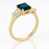 Gold ring with a blue gemstone and two clear stones on a white background
