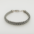 Silver braided bracelet on a light grey background