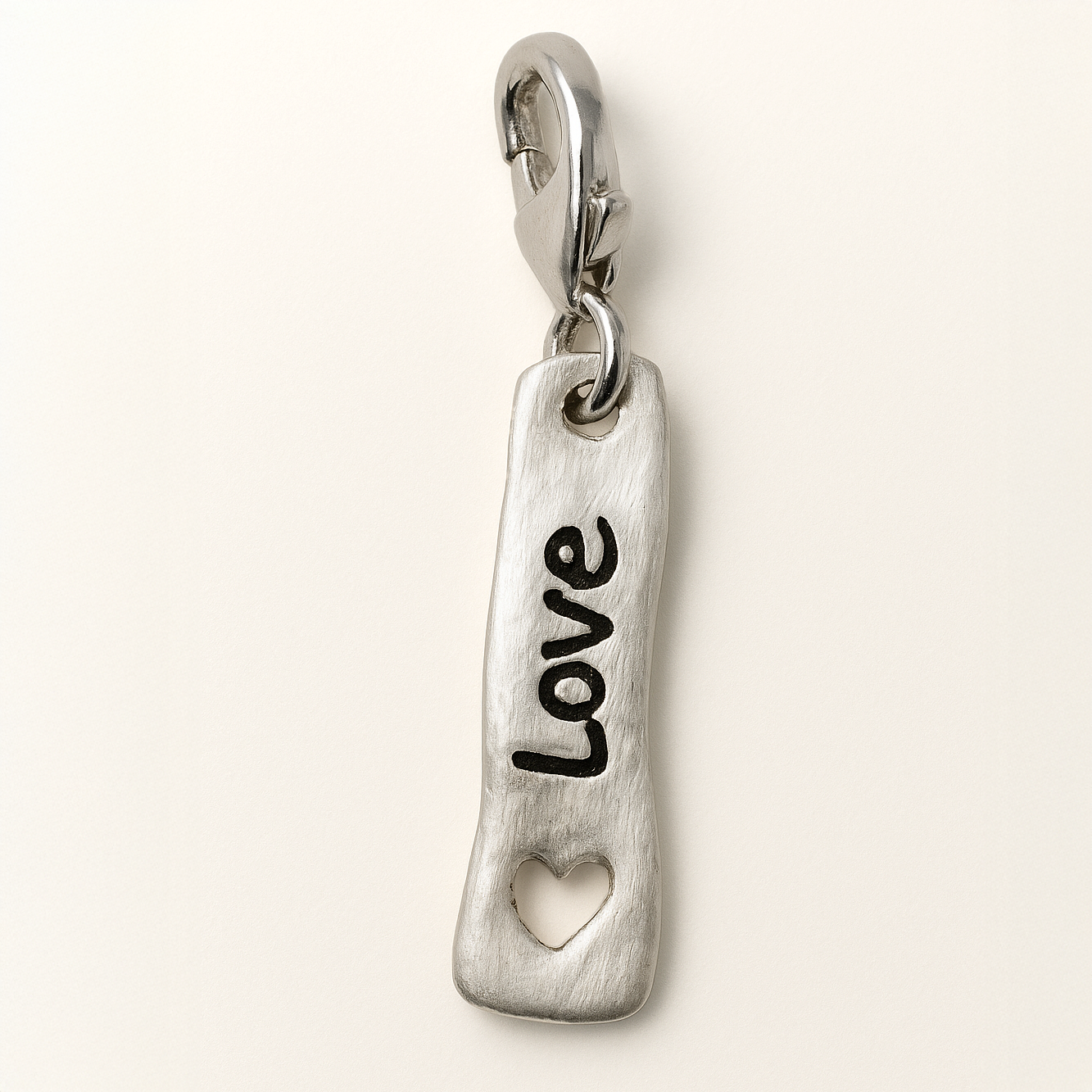 Silver charm with 'LOVE' engraving on a white background