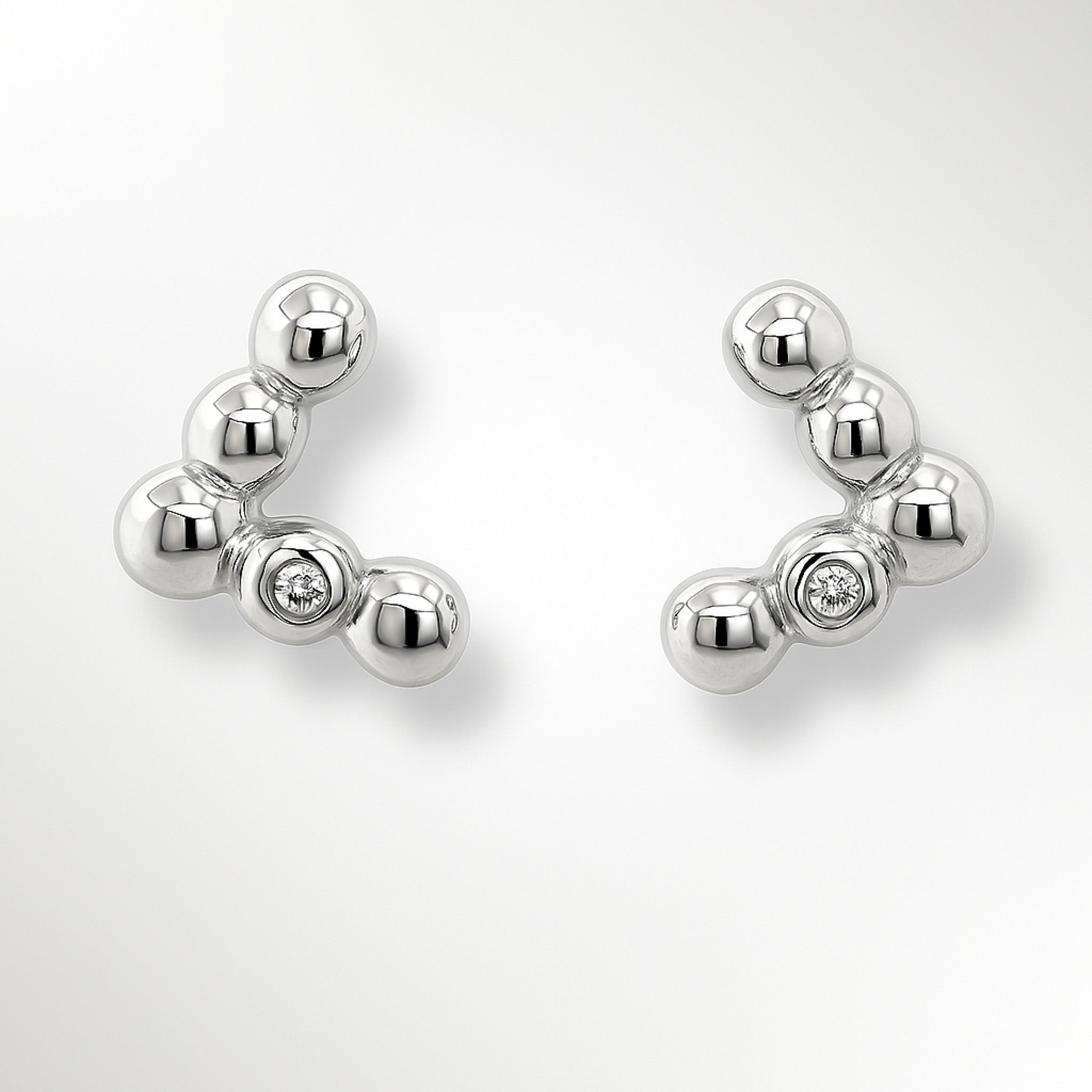Pair of silver earrings with small diamonds on a light grey background