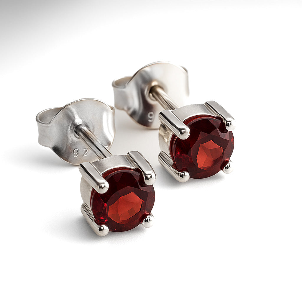 Silver stud earrings with red gemstones on a white background