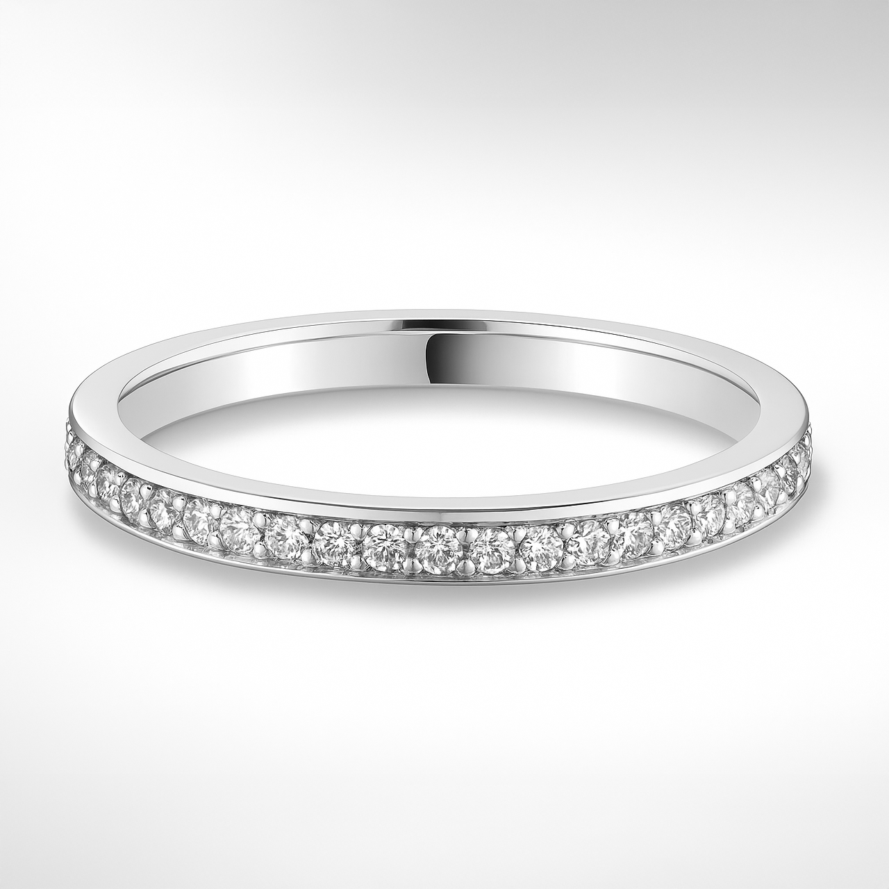 White gold wedding ring with small diamonds on a light grey background