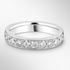 White gold wedding ring with small diamonds on a light grey background