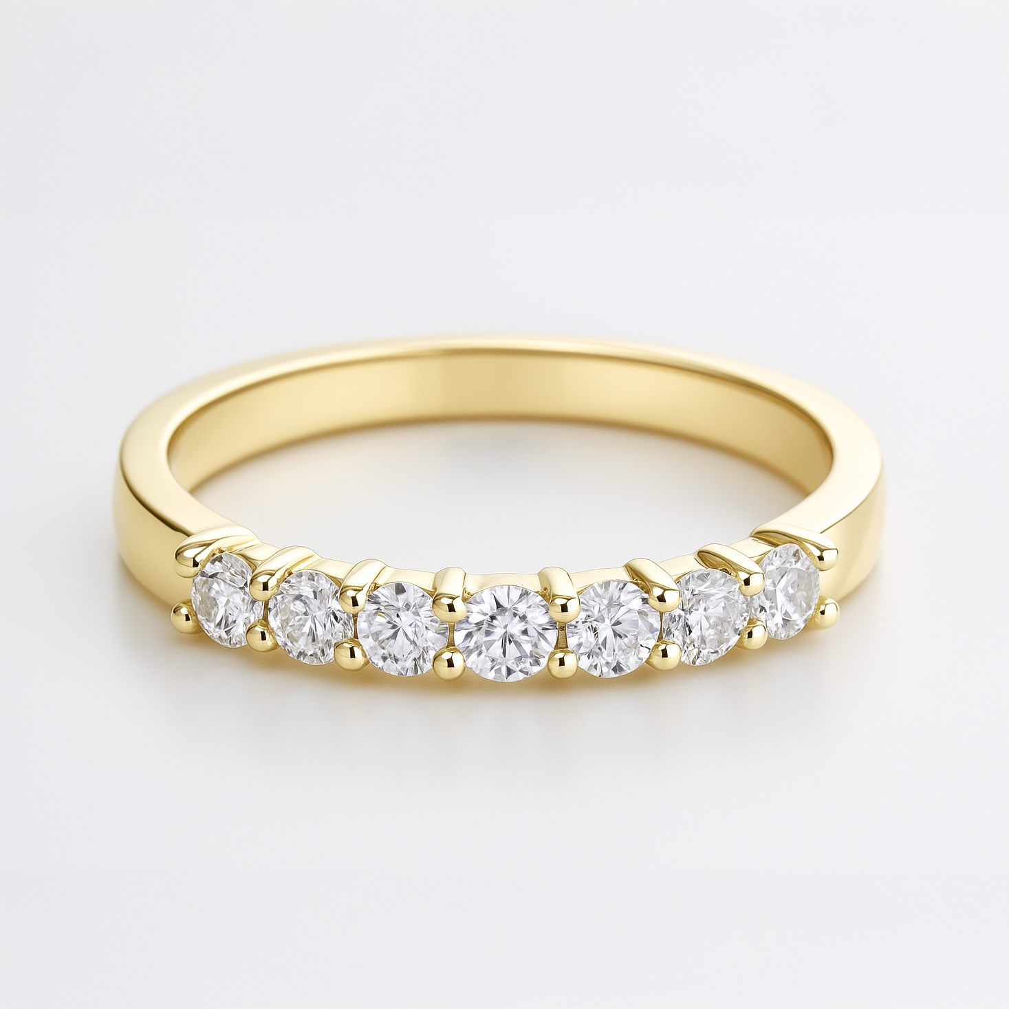Gold wedding ring with diamonds on a light grey background